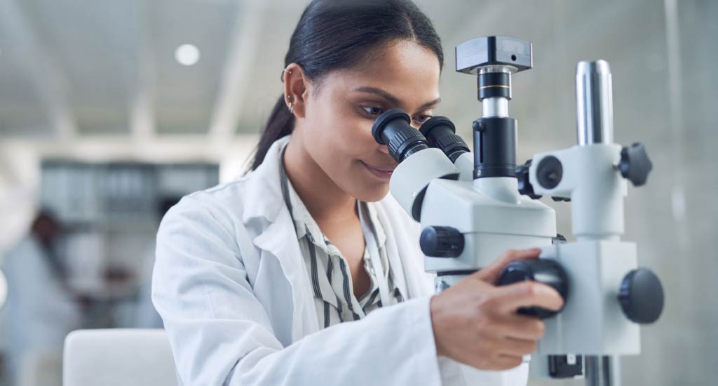 Quality control technician inspecting materials under a microscope to ensure quality standards.